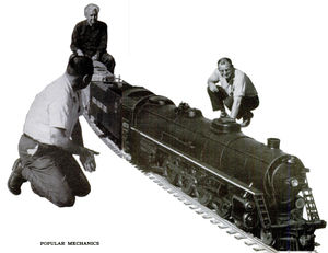Seymour F. Johnson rides astride diesel switch engine as he pushes steam locomotive and train over new section of 1.5 inch scale track to check its accuracy. From Popular Mechanics, August 1965.