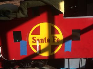 Two large 10 inch diameter "Santa Fe" logos were cut from yellow vinyl. Masking tape was applied adjacent to the location of the logo. Black marks were located on the tape by measuring from the bottom of the chassis. These marks were used as aids when applying the logo to keep it "level". The application tape has not yet been removed from the logo.