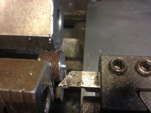The 3/4 inch round stock is mounted in the three jaw chuck. It is faced at 400RPM and a 1/32 inch chamber is cut around the edge. The part is not faced all the way to the center, as it will be drilled out. This lessens the chance of damaging the cutting tool.