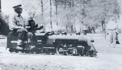 Buss Sutch riding as passenger on his 1-1/2 inch scale Atlantic at the Los Angeles Live Steamers Golden Spike event, 5 May 1957.