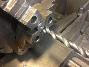 The final operation for this part is to debur the threaded hole. I placed a 7/16 inch drill in the tailstock, and gently applied pressure to the unlocked tailstock while turning the three jaw chuck by hand. One or two turns is all that is necessary. Be careful not to cut too deeply.