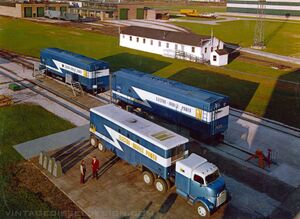 A well known press photo of the time, EMD held an event in LaGrange showcasing the new Electro-Mobile Power line, including two M-16 rail mounted power cars, and an MH-8 highway trailer. All of the equipment was painted in EMD Demonstrator Blue, with a white lightening stripe. EMD Photo