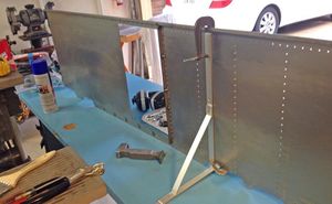 This is the setup I use to hold the panel while I am installing rivets. Makes it easier to reach both sides at the same time - rivet gun in front and bucking bar on back side.