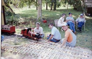 The Hot Penny being serviced by builder Marshall Black at the Browning Railroad, Chapel Hill, Texas. Track owner David Hannah III is wearing an orange shirt with coveralls. Front left to right: Marshall Black, Marty Knox, David Hannah III. Rear left to right: Jim Jackson and his wife, Marshall Phillips. About 1993. Photo by Terry Adams.