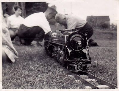 Norman Mottshaw's NYC Josslin 5200 in 3/4 inch scale. Note the Groovy Track using flat steel rails and slotted wood ties. Left to right: Helen Deachman, Jimmy Deachman, Norman Mottshaw. Photo provided by Pete Deachman.