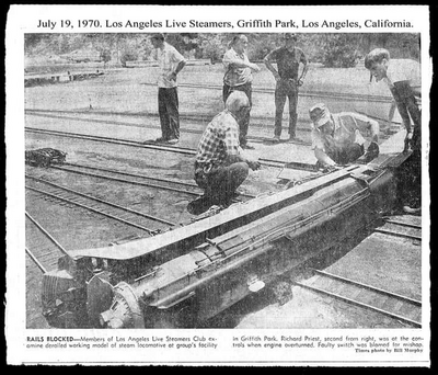 July 19, 1970, Los Angeles Live Steamers, Griffith Park, Los Angeles, California. Rails Blocked -- Members of Los Angeles Live Steamers Club examine derailed working model of steam locomotive at group's facility in Griffith Park. Richard Priest, second from right, was at the controls when engine overturned. Faulty switch was glamed for mishap. Times photo by Bill Murphy.