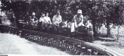 Approaching the station, David Hannah guides Fred Springer's engine across the trestle. In the cars behind him are Jim Jackson, Sheryl Pillegi, Dale Spring, and Fred Springer. The photo was taken at the first meet on the Browning Division on Labor Day 1987 by David Hannah, IV.